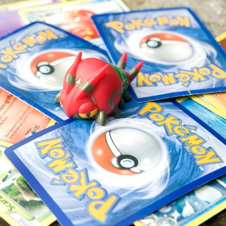 Pokemon-Sammelkarten auf einem Stapel und eine Pokemon-Figur (Archivbild)