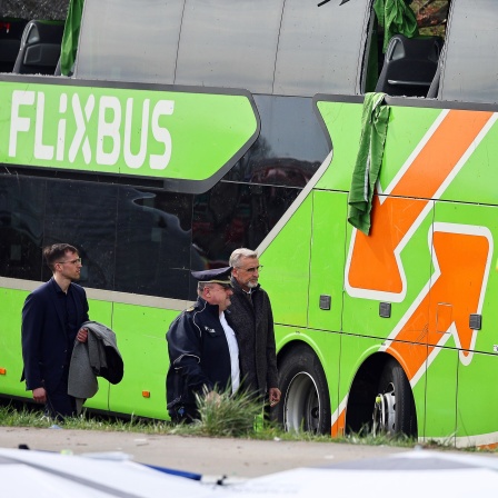 Politiker vor dem verunglückten, grünen Flixbus