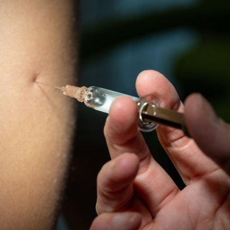 Eine Gynäkologin setzt eine HPV-Impfung bei einer Patientin.
