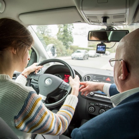 Ein Fahrlehrer erklaert (am 11.04.2019) in einem Fahrschulauto in Hamburg der Fahrschuelerin, wie sie das Lenkrad benutzen soll (Themenbild)