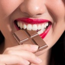 Eine Nahaufnahme von einer Frau, die in ein Stück Schokolade beißt.
