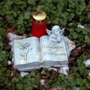 Eine Engelsfigur und ein Grablicht stehen auf einem Grab