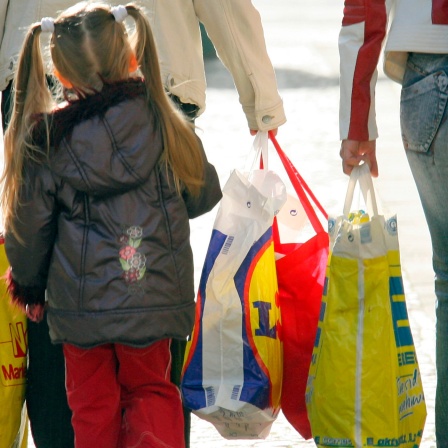 Ein Kind läuft hinter zwei Frauen, die Einkaufstüten tragen