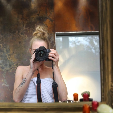 Spiegelbild einer Frau, die ein Foto mit einer Kamera macht.