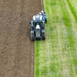 Ein Landwirt fährt mit einem Traktor zur frühjährlichen Bodenbearbeitung auf einem Feld