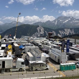 Dutzende Übertragungswagen und Wohnmobile, im Hintergrund die Alpen.