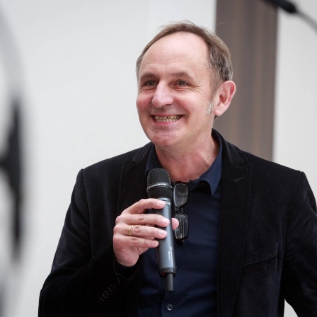 Portrait des Architekten Volker Staab mit einem Mikrofon in der Hand