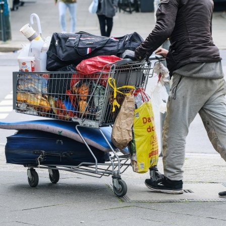 Obdachloser mit einem voll bepacktem Einkaufswagen