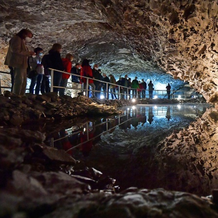 Besucher laufen durch die Barbarossahöhle