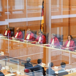 Der Erste Senat des Bundesverfassungsgericht sitzt in seinen roten Roben auf dem Richterpodium.