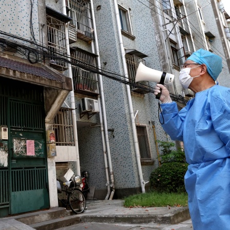Ein freiwilliger Helfer spricht ein Megaphon, um mit den Bewohnern eines Wohnhauses in Shanghai zu sprechen.
