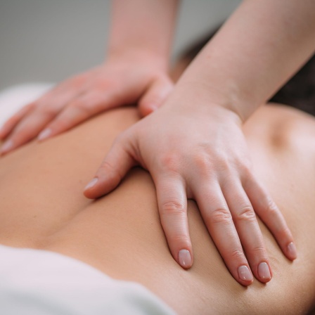 Eine Person auf einer Liege bekommt eine Rückenmassage