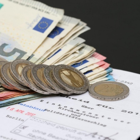 Symbolbild Steuererklärung, Steuerbescheid mit Euro-Münzen und -Scheinen