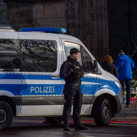 Menschen versammeln sich vor der Johanniskirche. Davor sperrt ein Fahrzeug der Polizei die Straße. Am Mittag ist dort eine Mahnwache geplant. Am 20. Dezember 2024 ist auf dem Weihnachtsmarkt in Magdeburg ein Autofahrer in eine Menschengruppe gefahren. Es gab mehrere Tote und Verletzte.