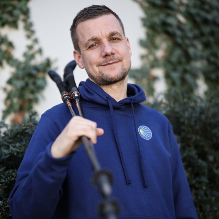 Tobi Schlegl, Journalist und Notfallsanitäter, hält seine Wanderstöcke bei einem Fototermin (17.03.2025, Hamburg)