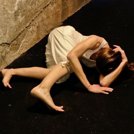 In einem engen Flur windet sich eine Frau auf dem Boden.