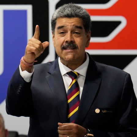 Präsident Nicolas Maduro trägt einen schwarzen Anzug und spricht gestikulierend.