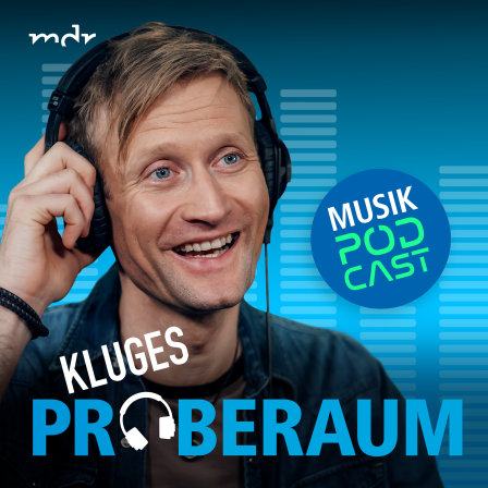 Der Podcast-Host Tobias Kluge lacht und hat Kopfhörer aufgesetzt.