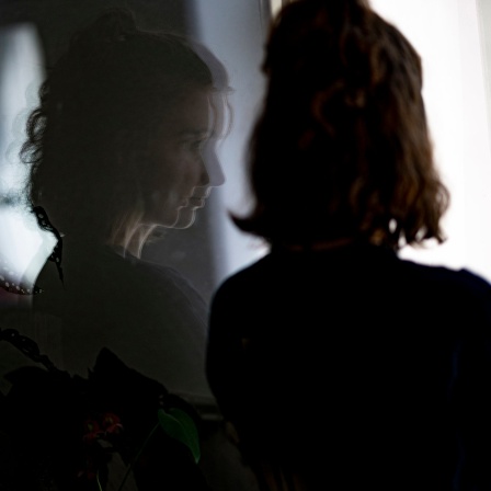 Das Beitragsbild des Dok5 "Tabu - Wenn ein Geheimnis das Leben im Griff hat" zeigt eine Frau alleine am Fenster stehend indem sie sich spiegelt.