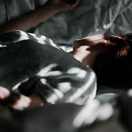 Eine Frau liegt bei Tageslicht im Bett