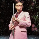 Der Musiker Jimi Tenor mit Querflöte, rosa Anzug und Goldrand-Brille im nächtlichen Schnee