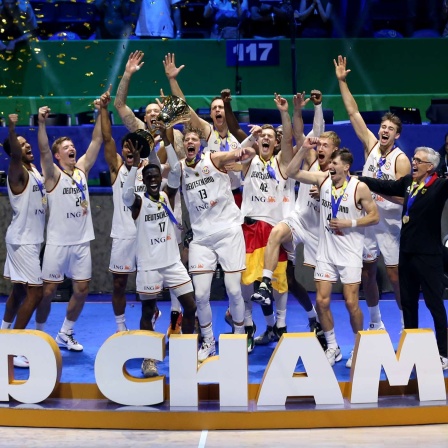 Deutschlands Dennis Schröder hebt den Pokal bei der Siegerehrung der Basketball-WM hoch und feiert mit dem Team den Titel.