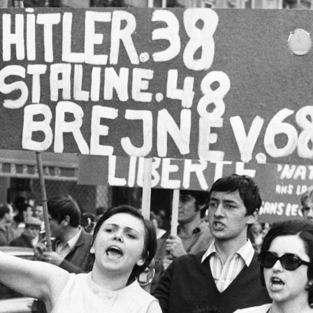 Menschen demonstrieren am 22. August 1968 in Prag gegen die Besetzung der Tschechoslowakei durch die Sowjetunion. Auf einem Plakat steht: &#034;Hitler 38, Stalin 48, Brejnev 68&#034;