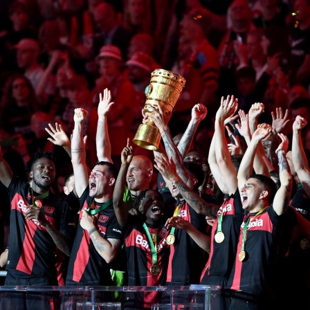 Leverkusens Mannschaft jubelt nach dem Sieg im DFB-Pokal gegen Kaiserslautern mit der Trophäe.