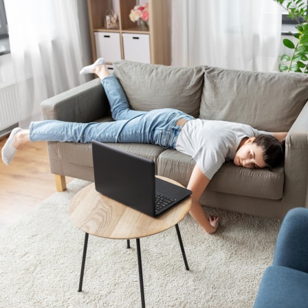Eine Frau liegt müde auf dem Sofa