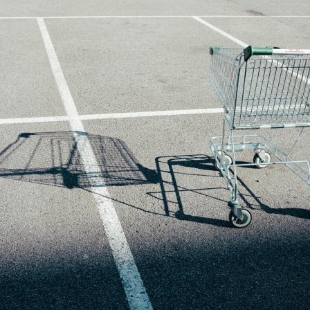 Ein leerer Einkaufswagen steht auf einem Parkplatz.