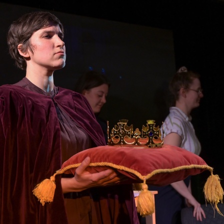 Die Schauspielerin Alessa Kordeck hält im Stück "König von Deutschland" die "Reichskrone", die auf einem Samtkissen liegt. 