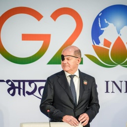 Bundeskanzler Olaf Scholz (SPD) steht mit Augenklappe vor dem Logo des G20-Gipfels in Neu Delhi in Indien.