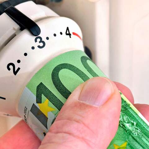 Hand mit Euroschein an Heiszungsthermostat, Symbolfoto Heizkosten (Bild: IMAGO / Wolfgang Maria Weber)