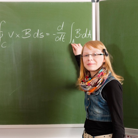Schülerin steht vor Tafel mit Formel