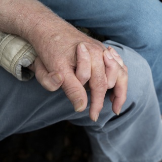 Ein Seniorenpaar hält sich bei den Händen. 