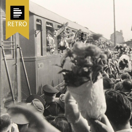 Ankunft von Heimkehrern aus der Kriegsgefangenschaft in der Sowjetunion in Wiener Neustadt. Winkende und Blumensträusse schwenkende Menschenmenge am Bahnsteig. 25. Juni 1955. 