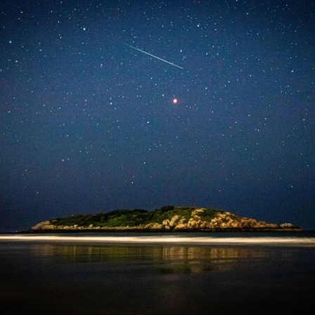 Meteor und Sternenhimmel über einer Insel