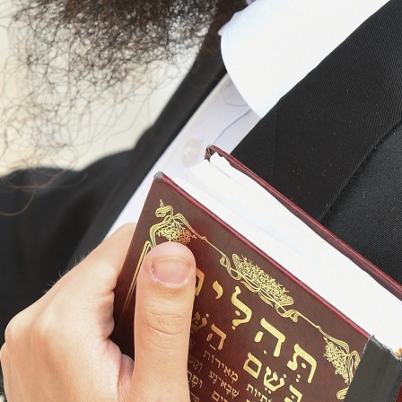 Ein orthodoxer Jude betet mit einerTora, einer hebraeischen Bibel unterm Arm, an der Klagemauer auf dem Tempelberg in Jerusalem.