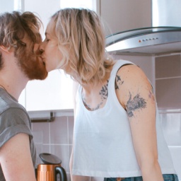 Eine Frau und ein Mann küssen sich in er Küche.