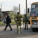Anwohner, die einen Unterschlupf im Stahlwerk Asovstal in Mariupol in der Ukraine verlassen haben, gehen zu einem Bus, der von Soldaten bewacht wird.