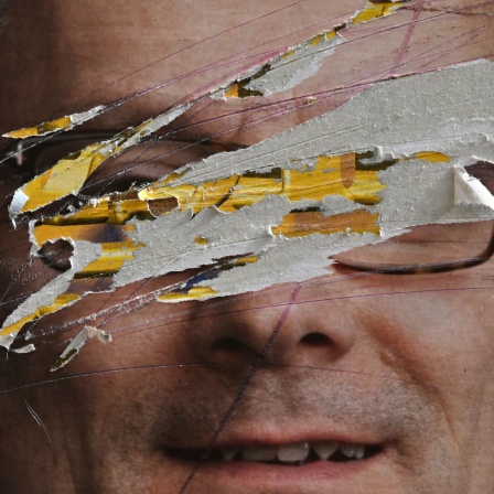 Das Gesicht eines Politikers auf einem Wahlplakat ist nicht zu erkennen, da es teilweise zerstört wurde.