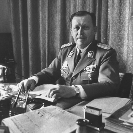Alfredo Stroessner sitzt an einem Schreibtisch und schaut in die Kamera