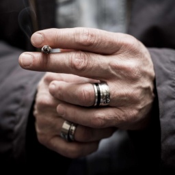 Die Hände eines Mannes mit Zigarette und dicken Ringen an den Fingern.