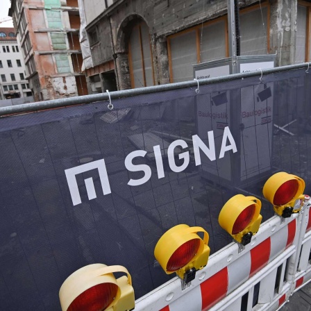 An einer Baustellenabsperrung ist das Logo von "Signa" zu erkennen.