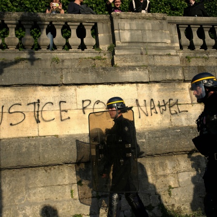 Französische Polizisten gehen in Paris an einer Wand vorbei, auf die &#034;Gerechtigkeit für Nahel&#034; gesprüht wurde, während sich Jugendliche zu einer Demonstration auf dem Place de la Concorde versammeln.