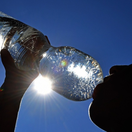 Junge trinkt Wasser aus einer Plastikflasche bei grosser Hitze