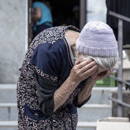 Ukraine: Eine alte, erschöpfte Frau hält ihren Kopf in den Händen
