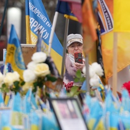 Eine Frau macht ein Foto an einem Denkmal für die Gefallenen des Kriegs mit Russland auf dem Unabhängigkeitsplatz in Kiew.
