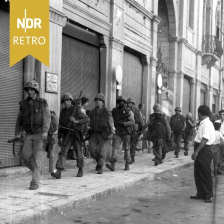 U.S. Marines gehen in Beirut gehen eine Straße entlang, in der die Geschäfte fest verschlossen sind, 17.07.1958.