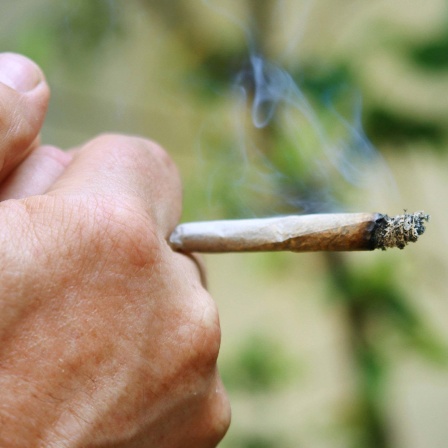 Nahaufnahme eines Joint in der Hand eines Mannes. 